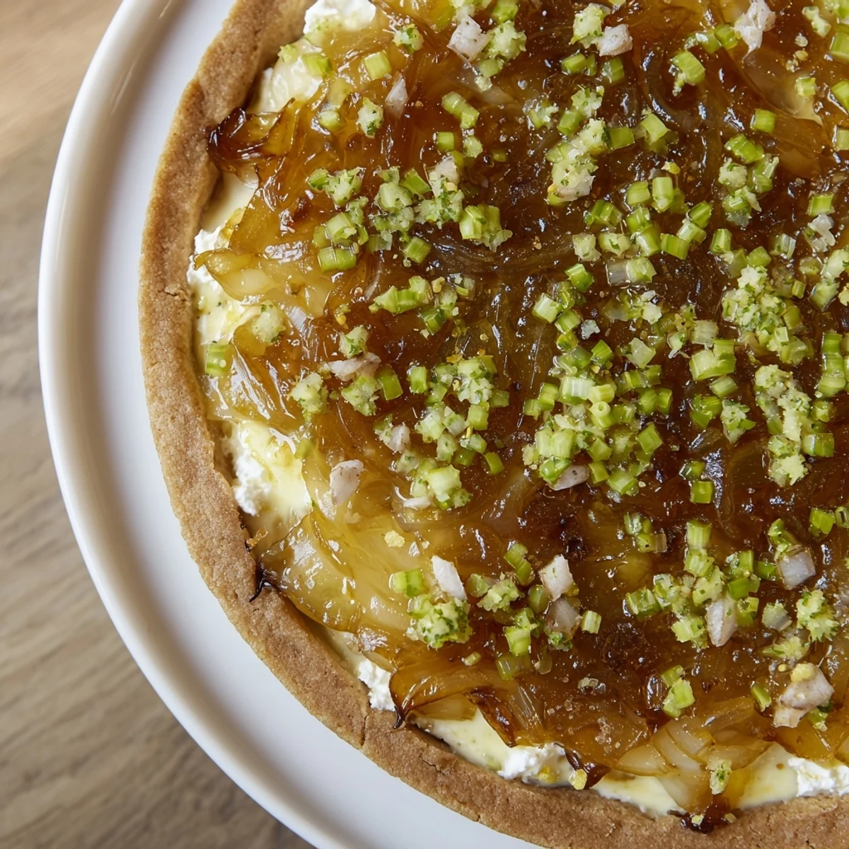 A close-up of a rustic, flaky Decadent Caramelized Onion and Goat Cheese Tart, ready to slice and enjoy.