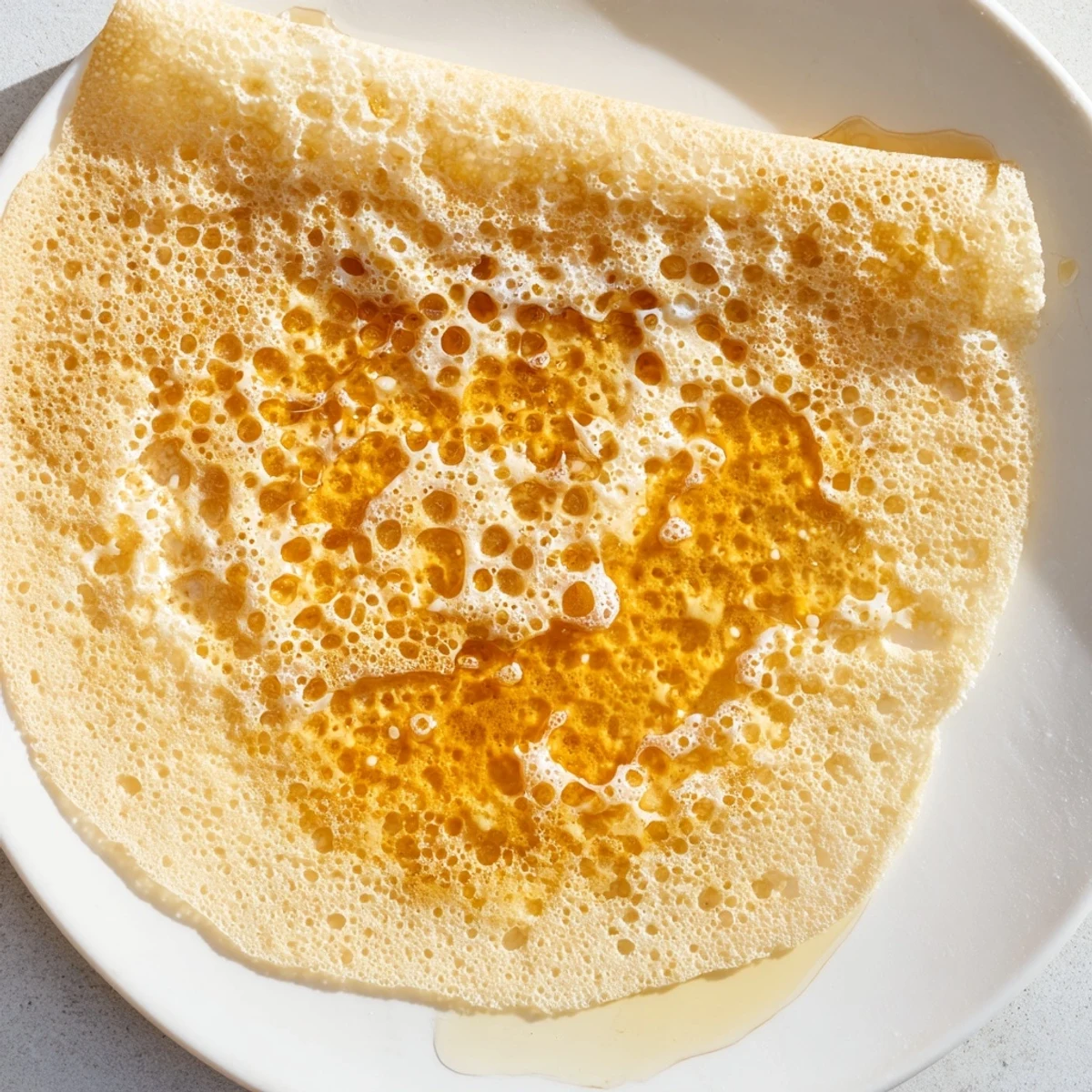 Golden Moroccan Baghrir crepes, perfectly porous, drenched in warm honey-butter for breakfast bliss.