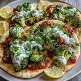 A finished vegetarian Harissa Broccoli and Flatbreads dish is served with creamy dollops of Greek yogurt and extra harissa sauce on the side.