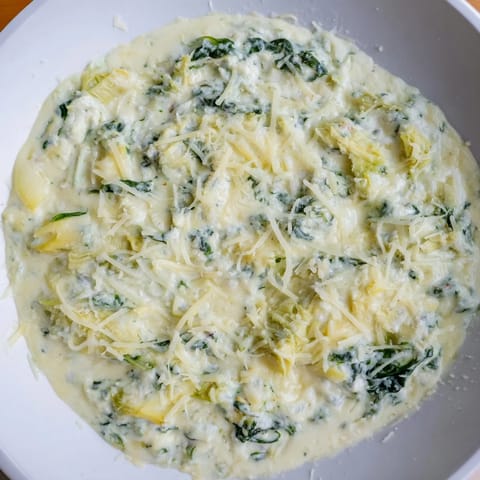 A close-up of creamy Cheesy Spinach Artichoke Dip, boasting melted cheese and artichoke pieces.