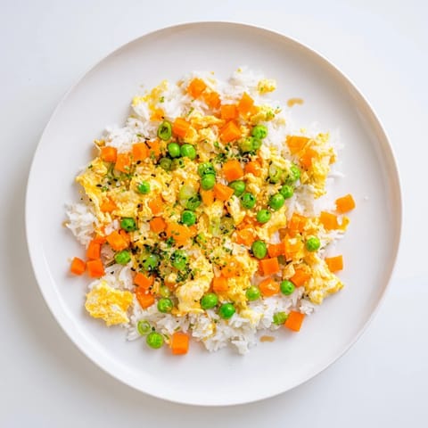 A steaming bowl of flavorful Egg Fried Rice, garnished with fresh scallions, ready to eat.