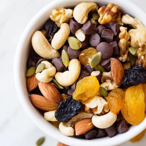 Colorful bowl of Trail Mix Custom with walnuts, sunflower seeds, raisins, and shredded coconut, ready to be portioned into portable bags for hiking or office energy boosts.
