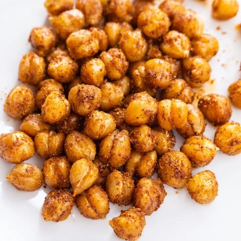 Spicy roasted chickpea snack tossed with garlic and cayenne, piled high on a baking sheet for easy snacking.