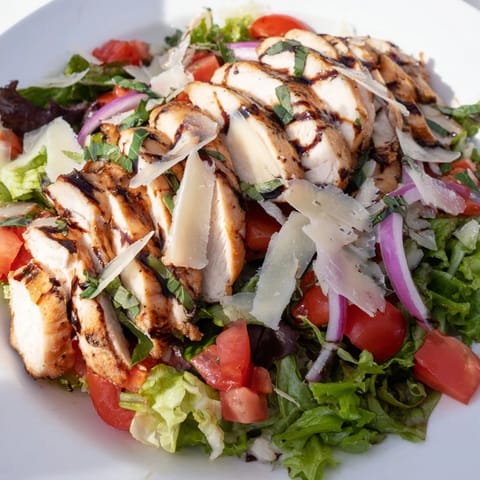 Vibrant bruschetta chicken salad with juicy grilled chicken, diced tomatoes, fresh basil, and shaved Parmesan, ready for a light lunch.