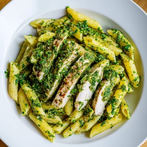 Golden, juicy chicken and pasta twirled in a vibrant, garlicky chimichurri drizzle, served with lemon wedges.