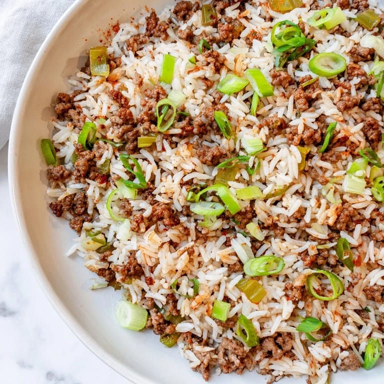 Close-up of a rustic bowl filled with golden-brown Cajun Dirty Rice, with visible spices and textures.