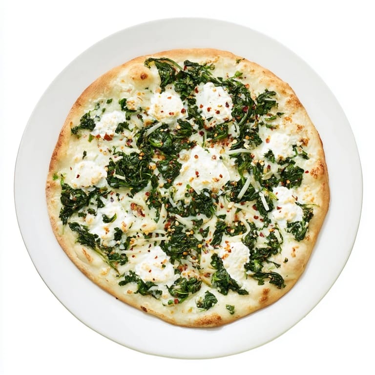 A close-up of the spinach ricotta pizza highlights golden, bubbling mozzarella and Parmesan over sautéed greens and garlic butter.