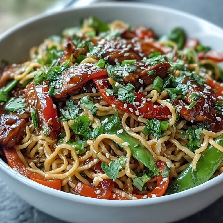 Freshly cooked Pork Noodle Stir-Fry tossed with julienned carrots and green onions in a hot wok.