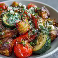 Freshly roasted Mediterranean Greek vegetables with caramelized edges, topped with crumbled feta, Kalamata olives, and parsley, served warm from the oven.